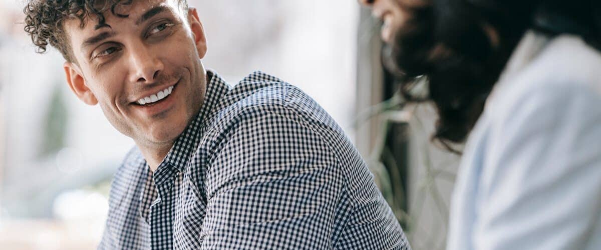 Caucasian man and black woman sharing a friendly smile indoors with natural light
