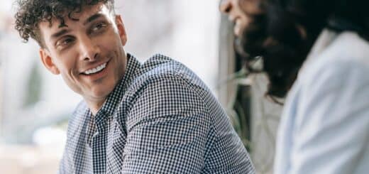 Caucasian man and black woman sharing a friendly smile indoors with natural light