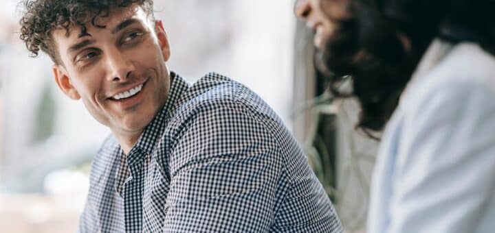 Caucasian man and black woman sharing a friendly smile indoors with natural light
